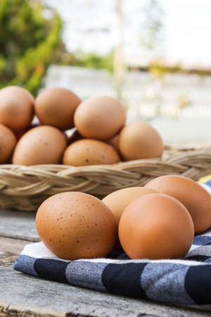 Eggs on tablecloth over wooden table. With eggs in a basket are background.の写真素材