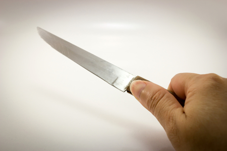 Hand holding knife on white background.