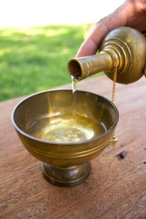 Buddhist's grail pouring water by oldman's hand.の写真素材