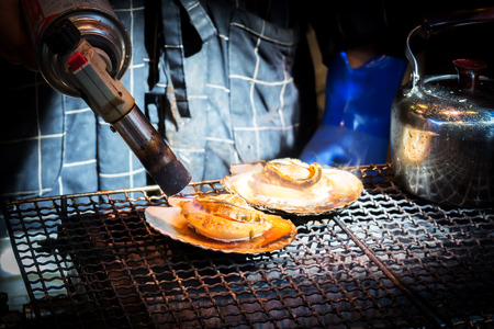 Closeup shell on grill. Action of burning shell by Butane torch. Street Seafood in favorite fish maket in Japan.の写真素材