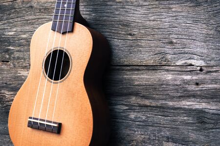 Ukulele with wooden background. Acoustic music instrument. Art and  music background. Vintage style with fade color tone. And dark vignette. Hi contrast style.の写真素材