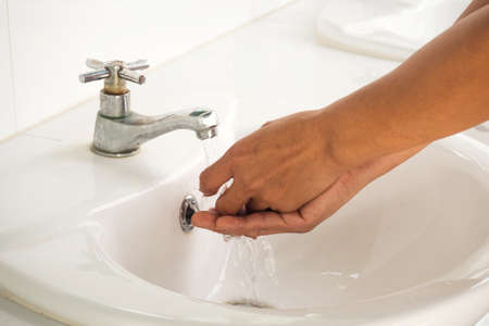 Woman hands washing under clean water pour. In white bowl on public rest room.の写真素材