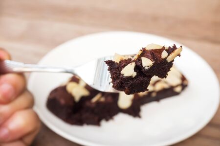 Woman hand holding fork picking sliced homemade brownies. Favorite dessert for chocolate lover....