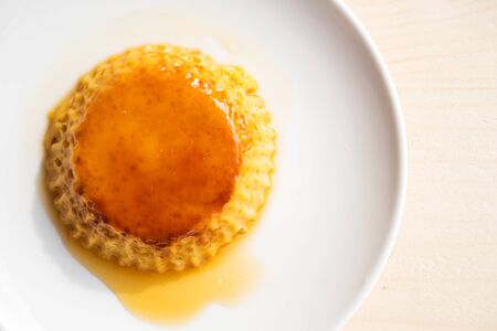 Homemade custard pudding on white plate. Over wooden table. Sweet dessert. Top view.の写真素材