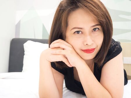 Asian woman smiling. Portrait woman laying down on bed. Closeup on face.の写真素材