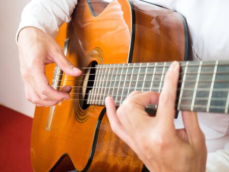 Closeup young Asian man play guitar. Classical music instrument. String equipment. Art and music...