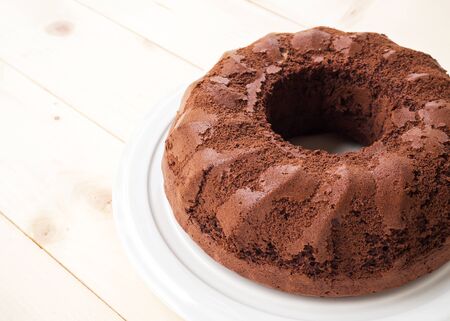 Chiffon chocolate cake on  white plate. Over wooden table. Plain cake in ring shape. Favorite dessert for chocolate lover. With copy space.の写真素材