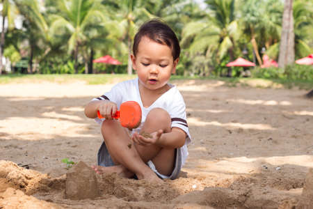Cute Asain child playing sand on beach. Favorite activity of summer vacation.の写真素材