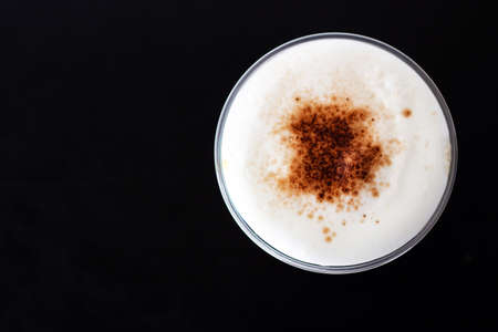 Ice cappuccino in plastic cup. Top view of milk foam and cinnamon powder topping. Refreshment...