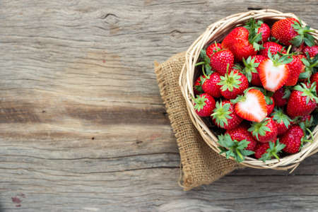 Fresh strawberry in bamboo basket on wooden table. Healthy and sweet fruit. Top view with copy...