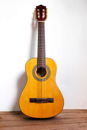 Classic guitar on wood floor with white wall. Favorite string music instrument. Music background.の写真素材