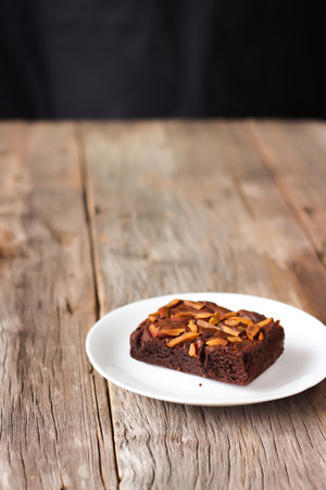 Homemade brownie on white plate. Sweet dessert with cocoa and coffee. Served on white plate over wooden table.の写真素材