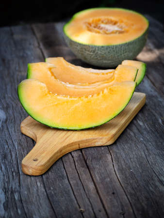Sliced fresh sweet melon on wooden board. Orang texture and juice tast of fruit. Dark food style.