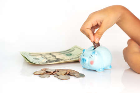 Asian girl putting dollar coin in piggy bank. Concept of saving money on white background.
