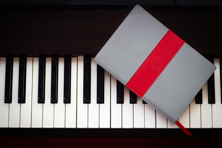 Notebook on piano key. Top view with copy space. Concept of take a note of song.の写真素材