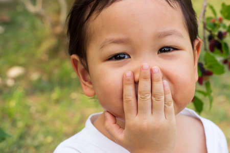 Asian child laughing gag. Close up in her eyes. Natural action of children feeling happiness and shy.の写真素材