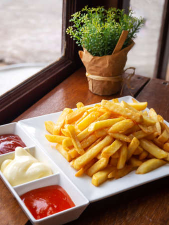 French fries on white plate served with chili, tomato sauce and mayonnaise. Favorite snack of American junk food.の写真素材