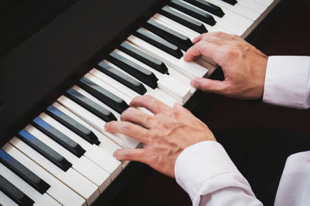 Closeup hand man playing piano. Classical music instrument. Fade color tone.
