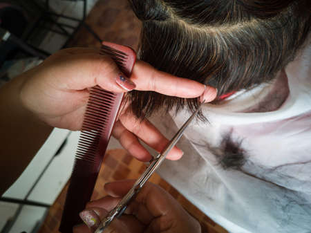 Close-up of a hairdresser cutting the hair of a customer in a beauty salon