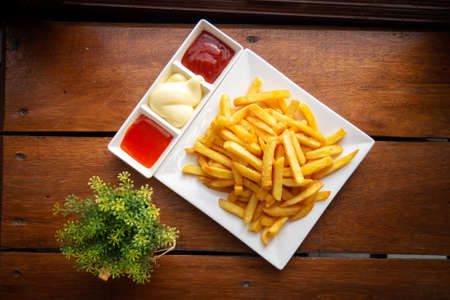 French fries on white plate served with chili, tomato sauce and mayonnaise. Favorite snack of...