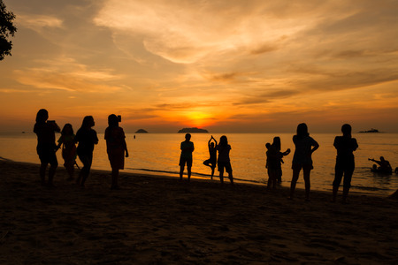 Silhouettes of people enjoying sunset on the  beach at Koh chang island, Thailandの写真素材