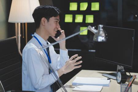 Smiling businessman dressed in white shirt sitting in cafe and using tablet computer while talking by his phone. Look aside.の写真素材