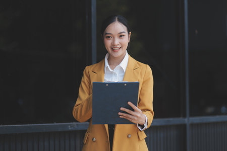 Portrait of a successful business woman using digital tablet in front of modern business buildingの写真素材