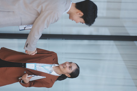 Young female and male businesspeople shaking hands after a successful meeting in front of an office building. Low angle view. Working in urban city streetsの写真素材