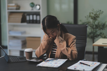 Asian women are stressed while working on laptop, Tired asian businesswoman with headache at office, feeling sick at work, copy spaceの写真素材