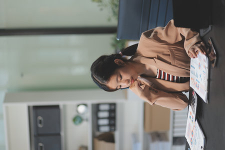 telework concept - Asian business woman uses laptop computer to join video meeting and writes notes on her digital tablet at homeの写真素材