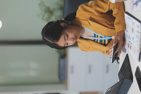Accountant, Asian independent business woman uses calculator to calculate company financial results on table in office and business work history, tax, accounting, statistics and analytical concepts.の写真素材