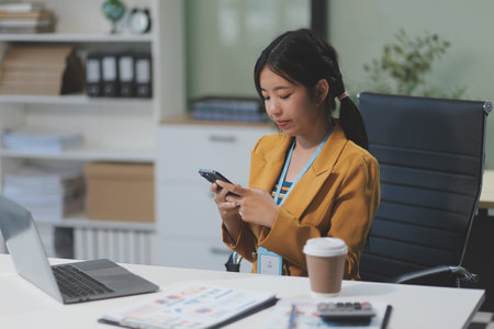 Asian Businesswoman Using laptop computer and working at office with calculator document on desk, doing planning analyzing the financial report, business plan investment, finance analysis concept.の写真素材