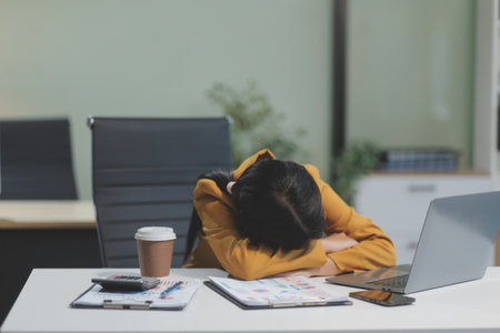 Asian women are stressed while working on laptop, Tired asian businesswoman with headache at office, feeling sick at work, copy spaceの写真素材