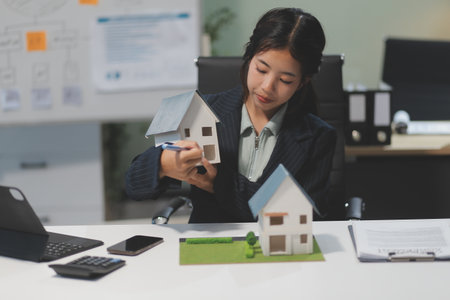 Real estate agents explain models of housing estates in projects to elaborate to clients, explaining and presenting information about homes and purchasing loans. Real estate trading concept.の写真素材