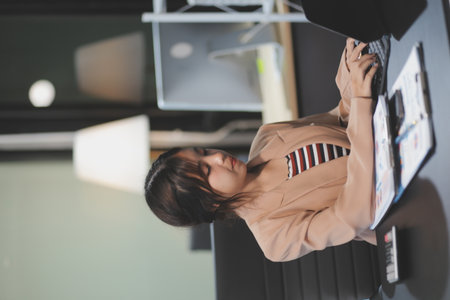 telework concept - Asian business woman uses laptop computer to join video meeting and writes notes...
