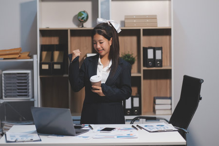 Excited happy Asian woman looking at the phone screen, celebrating an online win, overjoyed young asian female screaming with joy, isolated over a white blur backgroundの写真素材