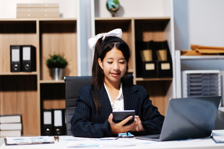 Portrait of Young Asian woman hand freelancer is working her job on computer tablet in modern office. Doing accounting analysis report real estate investment data, Financial and tax systems concept.の写真素材