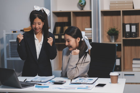 Two young Asian business woman talk, consult, discuss working with new startup project idea presentation analyze plan marketing and investment in the office.の写真素材