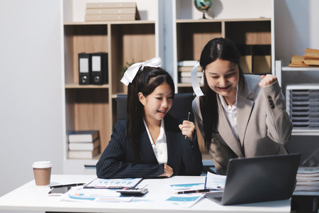 Two young Asian business woman talk, consult, discuss working with new startup project idea...