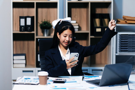 Excited happy Asian woman looking at the phone screen, celebrating an online win, overjoyed young asian female screaming with joy, isolated over a white blur backgroundの写真素材