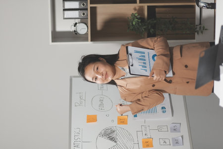 Asian Businesswoman Using laptop computer and working at office with calculator document on desk, doing planning analyzing the financial report, business plan investment, finance analysis concept.の写真素材