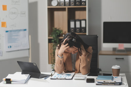 Asian women are stressed while working on laptop, Tired asian businesswoman with headache at office, feeling sick at work, copy spaceの写真素材