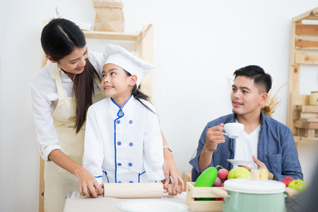 Happy family cooking biscuits together in kitchen at home for familyの写真素材