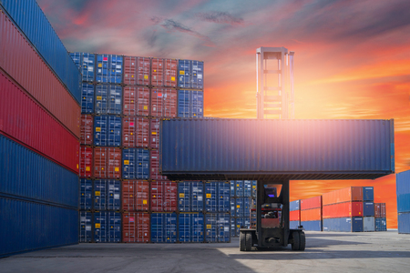 Forklift truck lifting cargo container in shipping yard or dock yard against sunrise sky for transportation import, Export and logistic industrial, Business logistic concept, Import and export conceptの写真素材