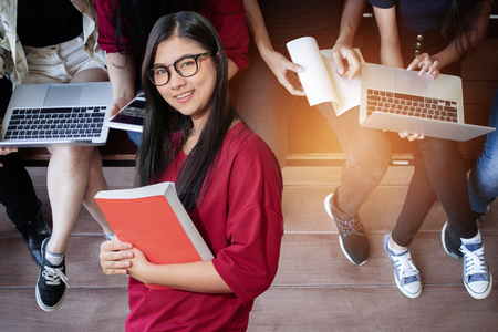 Education first, Beautiful female college student holding her books smiling happily standing in an auditorium people education learning high school program smart teenager concept copy spaceの写真素材