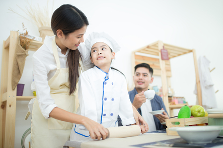 Happy family cooking biscuits together in kitchen at home for familyの写真素材