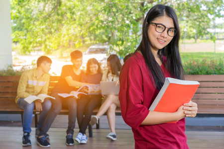 Education first, Beautiful female college student holding her books smiling happily standing in an auditorium people education learning high school program smart teenager concept copy spaceの写真素材