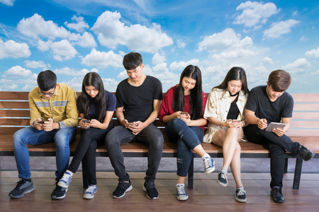 Closeup group adult hipsters friends sitting sofa using hands modern smartphone tablet.Business startup friendship teamwork concept.People working together project.Coworking process studio.の写真素材