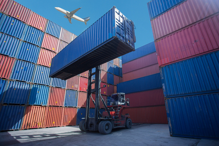 Forklift truck lifting cargo container in shipping yard or dock yard against sunrise sky for transportation importの写真素材