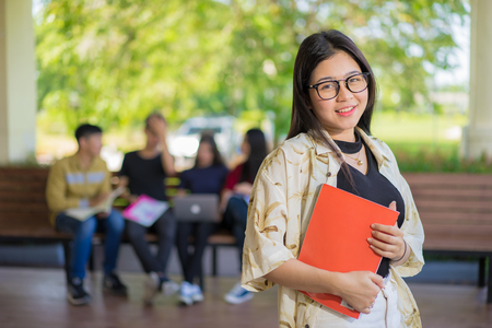 Education first, Beautiful female college student holding her books smiling happily standing in an auditorium people education learning high school program smart teenager concept copy spaceの写真素材